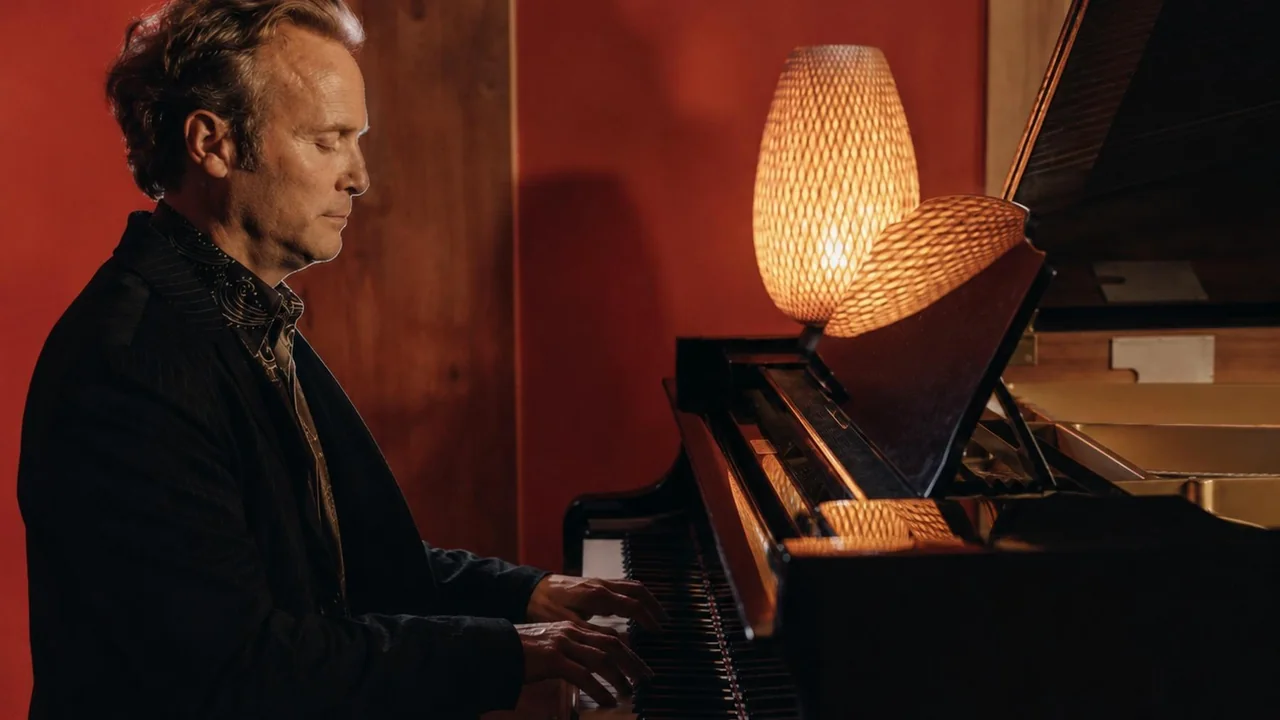 Howard Anderson performing piano in a warmly lit studio